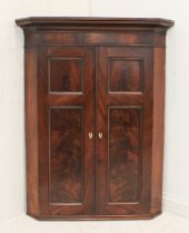 A mid-19th century mahogany corner cupboard - the flared, moulded cornice over a flame mahogany
