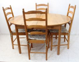 An Ercol oval-topped extending pine dining table on turned legs, together with a set of four