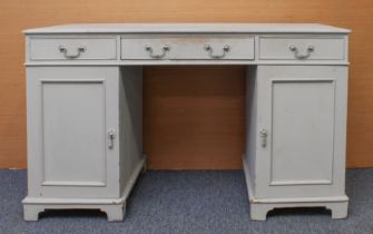 A grey-painted double pedestal desk: first half 20th century, the moulded top over three frieze