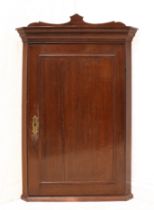 A George III oak corner cupboard - the moulded cornice with shaped cresting, over a fielded panelled