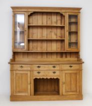 A Victorian-style waxed pine Welsh dresser - the flared, ogee moulded cornice over three open