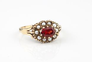 A 9ct yellow gold, pearl and garnet cluster ring - hallmarked Birmingham 1989, the oval cut garnet