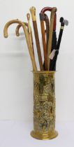 A cylindrical brass stick stand (48 cm high) containing nine walking sticks and two umbrellas