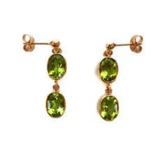 A pair of 9 carat gold dropper earrings each set with two oval-cut peridot stones.