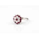 An 18ct platinum and white gold, ruby and diamond cluster ring - stamped 'PLAT' and '18CT', with a