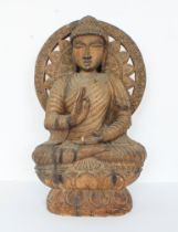 An Oriental carved wooden figure of the Buddha seated: 20th century, seated before a floral sunburst