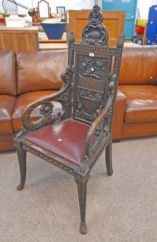 LATE 19TH CENTURY OAK OPEN ARMCHAIR WITH CARVED COAT OF ARMS BACK ON DECORATIVE QUEEN ANNE SUPPORTS