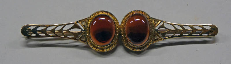 19TH CENTURY YELLOW METAL PIERCE WORK BROOCH SET WITH 2 OVAL CABOCHON GARNETS STUDDED WITH ROSE CUT