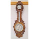 EARLY 20TH CENTURY CARVED OAK ANEROID BAROMETER WITH CIRCULAR CLOCK WITH WHITE ENAMEL FACE TO TOP