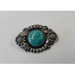 DANISH SILVER BROOCH WITH A POLISHED AMAZONITE ROUNDED TO CENTRE WITHIN A FLORAL BORDER BY KAY