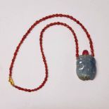 CHINESE CARVED TOURMALINE SCENT BOTTLE WITH CARVED DECORATION ON A RED SPINEL BEAD NECKLACE WITH AN