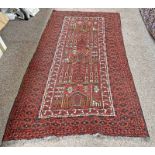 RED GROUND MIDDLE EASTERN RUG WITH VILLAGE/TEMPLE SCENE TO CENTRE PANEL,