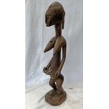 IGE AFRICAN STANDING FEMALE FIGURE HOLDING A BABY, CARVED WOODEN FORM, LARGE PRONOUNCED BREASTS,
