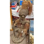 LARGE AFRICAN CARVED KNEELING FIGURE OF A WOMAN WITH WOVEN AND FRINGED GRASS SKIRT, ARMBANDS,