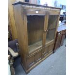 ERCOL ELM BOOKCASE WITH SHELVED INTERIOR BEHIND 2 GLAZED PANEL DOORS OVER 2 PANEL DOORS.