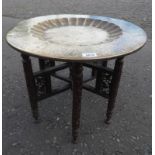 EASTERN STYLE BRASS TRAY TABLE WITH ETCHED DECORATION ON CARVED HARDWOOD BASE, DIAMETER 54.