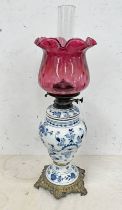 BLUE & WHITE PORCELAIN BODIED PARAFFIN LAMP WITH CRANBERRY GLASS SHADE