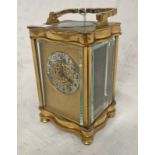 GILT METAL CARRIAGE CLOCK WITH SILVERED CIRCULAR DIAL ON TURNED SUPPORTS,