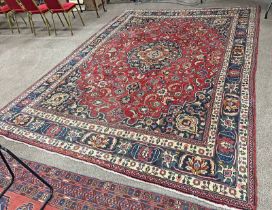 IRANIAN CARPET RED GROUND WITH A MULTICOLOURED BORDER FROM THE MASHHAD REGION OF IRAN 290 X 390CM