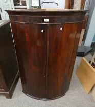 19TH CENTURY MAHOGANY BOW FRONT CORNER CABINET WITH SHELVED INTERIOR BEHIND 2 PANEL DOORS.