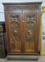 19TH CENTURY OAK 2 DOOR WARDROBE WITH 2 DECORATIVE CARVED PANEL DOORS WITH MASK DECORATION,