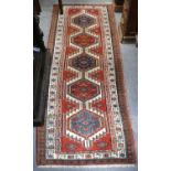 A Sarab Runner, the madder field with a column of stepped medallions framed by ivory borders,