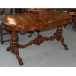 A Victorian Walnut Serpentine Center Table, the moulded top raised on carved and gadrooned