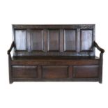 A George III Joined Oak Box Settle, 3rd quarter 18th century, the carved top rail above five fielded