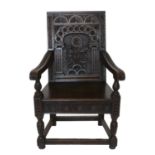 A Victorian Joined Oak Wainscot Armchair, in 17th century style, the back support carved with a