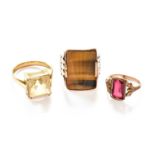 Three Rings, comprising of a citrine example, a tiger's-eye example and a red glass example, of
