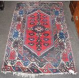 A Dosemealti Rug, the crimson lozenged field enclosed by hooked motif borders, 180cm by 118cm,