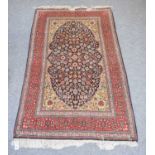 An Oriental Rug, the indigo floral field framed by cusped spandrels and brick red floral borders,