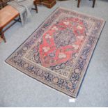 A Kashan Rug, the faded terracotta field centred by a medallion enclosed by spandrels and indigo