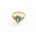 An 18 Carat Gold Emerald and Diamond Cluster Ring, the round cut emerald, in a white rubbed over