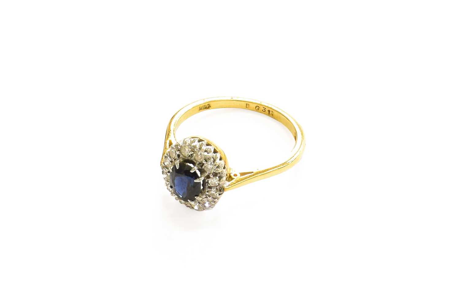 An 18 Carat Gold Sapphire and Diamond Cluster Ring, the oval cut sapphire within a border of eight-