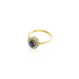 An 18 Carat Gold Sapphire and Diamond Cluster Ring, the oval cut sapphire within a border of eight-