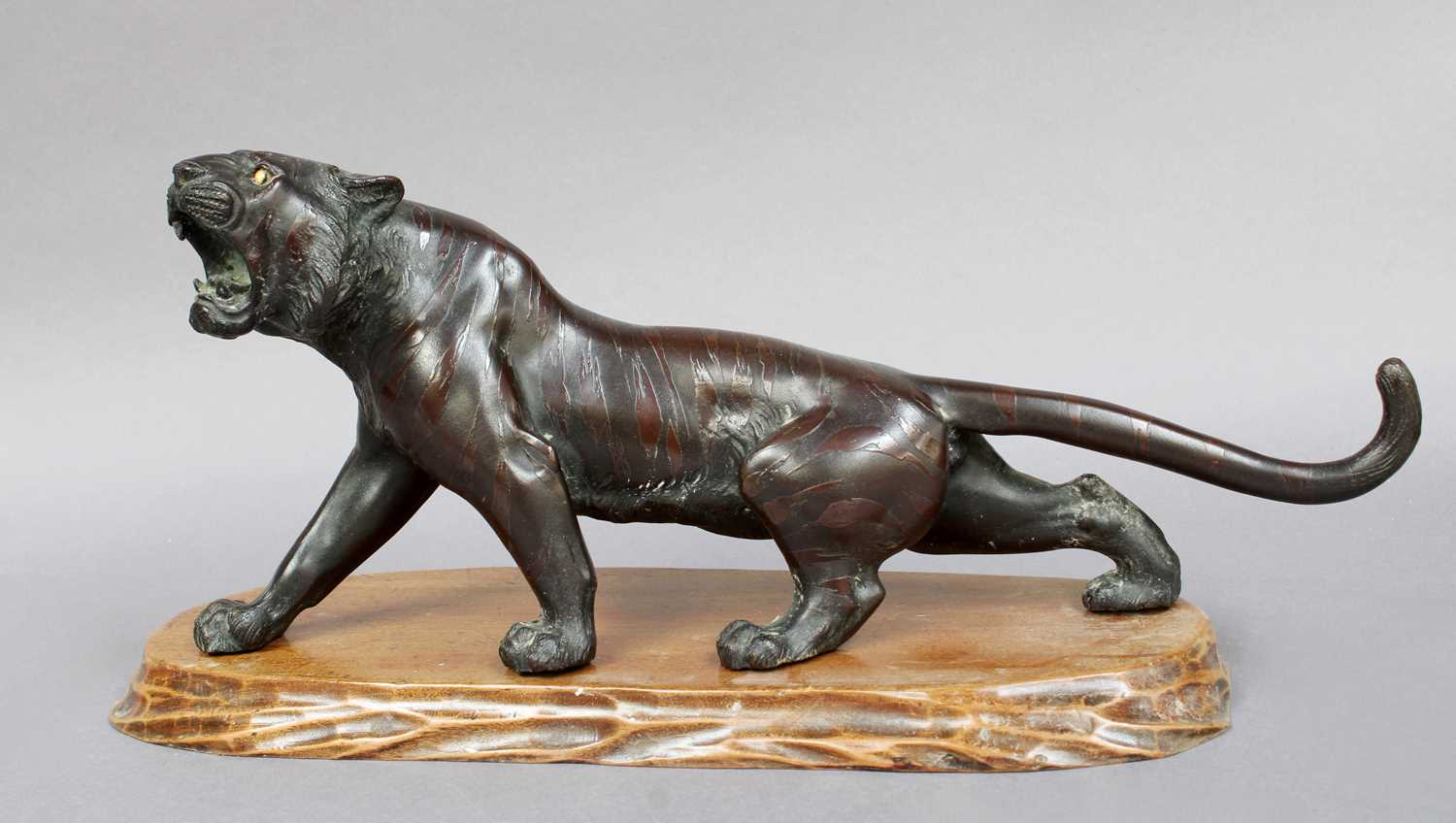 A Japanese Meiji Period Bronze Figure of a Stalking Tiger, on a wooden plinth, 32cm long Missing one