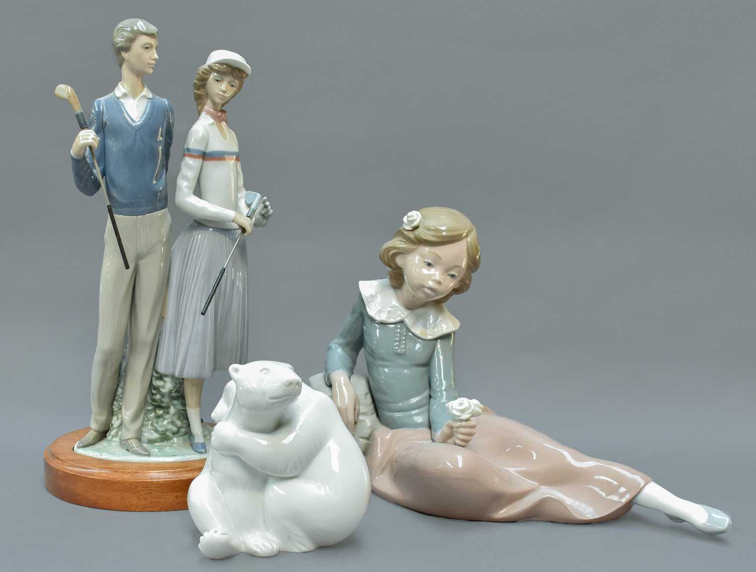 A Lladro Figure Group of Golfers, 36cm high; together with a Nao figure of a girl and a Berlin