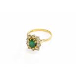 An 18 Carat Gold Emerald and Diamond Cluster Ring, the rectangular step cut emerald in a yellow claw