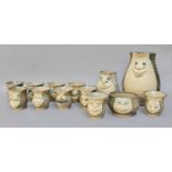 A 1970s Muggins pottery hot chocolate set, comprising ten face mugs, sugar bowl, a large jug and
