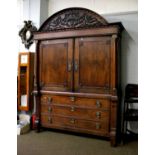 An Imposing 19th Century Carved Oak Armoire, circa 1830, the arched pediment decorated with