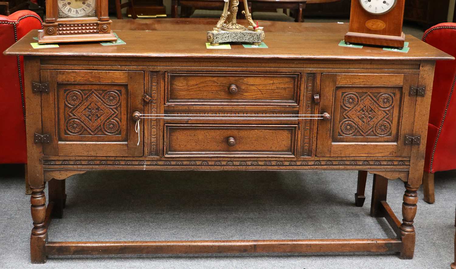 An Oak Side Board in 17th Century Style, with carved panel cupboard doors, flanking two drawers,