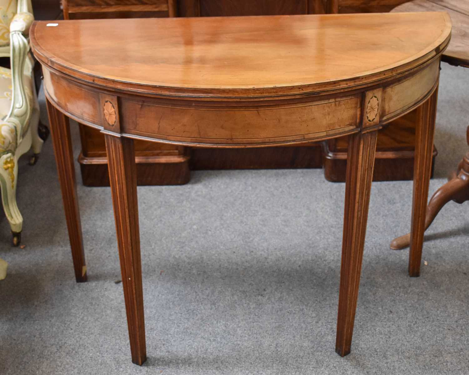 A George III Mahogany Demi Lune Fold Over Card Table, cross banded with fan paterer and on reeded