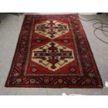 A Hamadan Rug, the deep brick red field with two stepped medallions enclosed by leaf and rosette