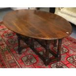 An Oak Oval Drop Leaf Coffee Table, 17th century style, on turned supports and with bar