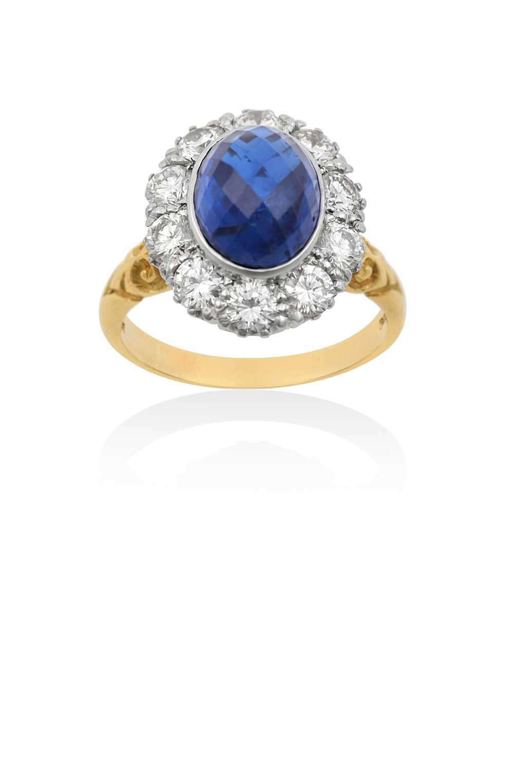 An 18 Carat Gold Sapphire and Diamond Cluster Ringthe faceted oval cabochon sapphire in a white