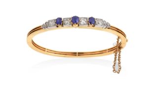 A Sapphire and Diamond Banglethree round cut sapphires in yellow claw settings alternate with old