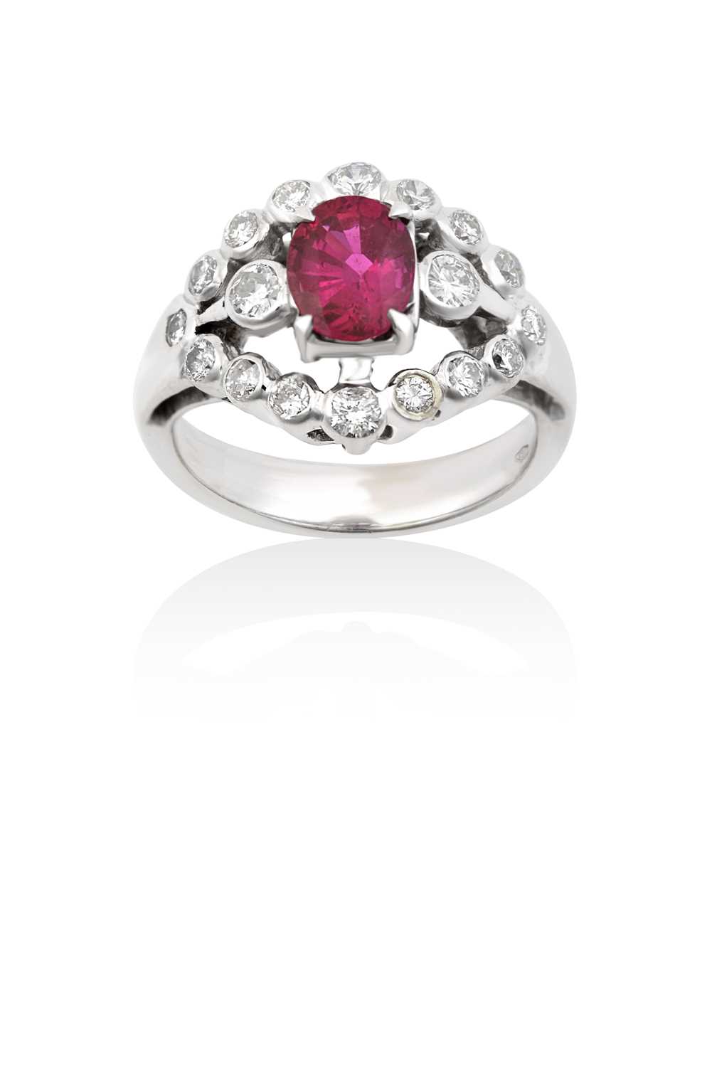 A Ruby and Diamond Cluster Ringthe oval cut ruby in a white claw setting, flanked by round brilliant