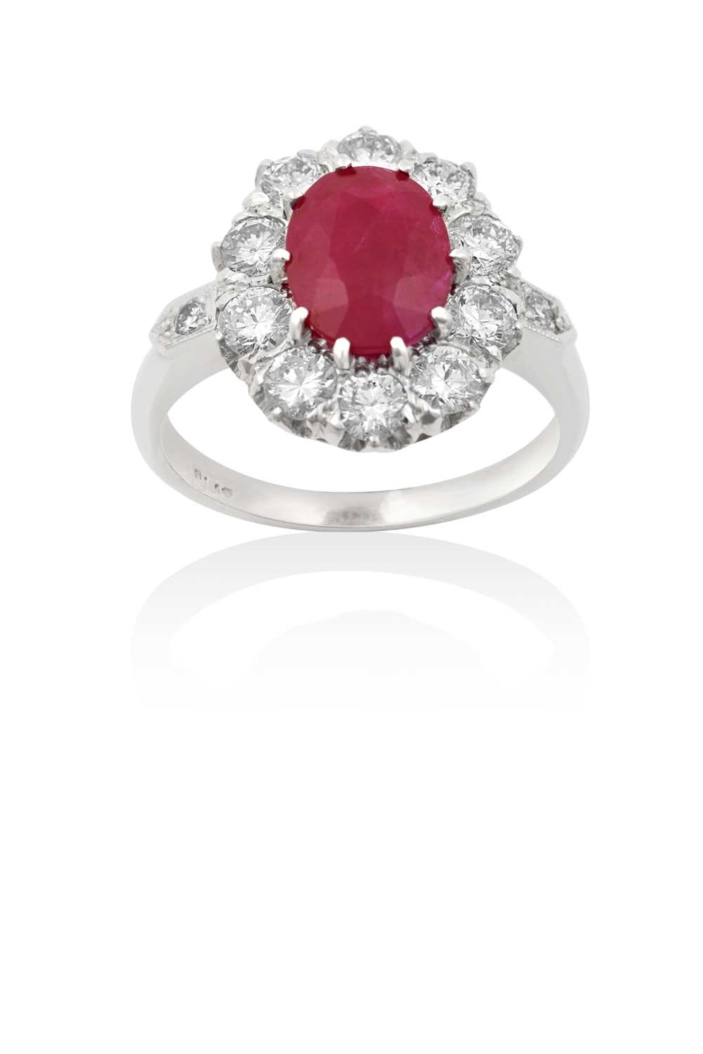 A Ruby and Diamond Cluster Ringthe oval cut ruby within a border of round brilliant cut diamonds, in