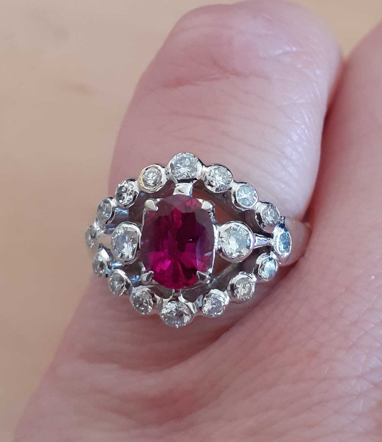 A Ruby and Diamond Cluster Ringthe oval cut ruby in a white claw setting, flanked by round brilliant - Image 3 of 4